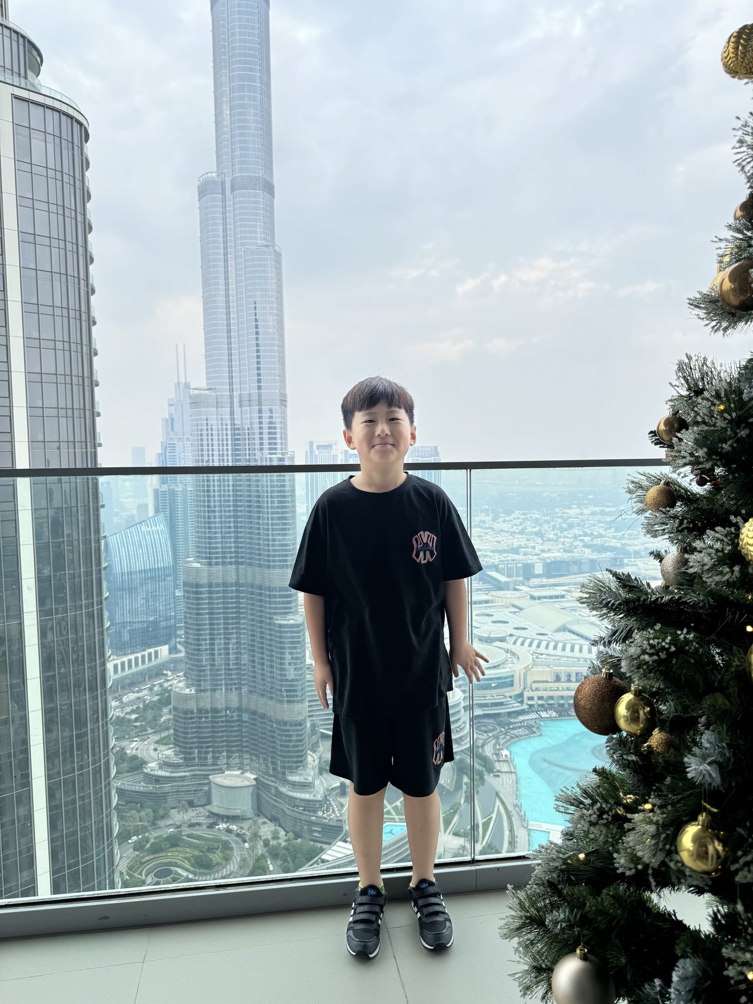 赵俊熙站在窗边，身后是城市建筑